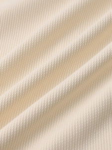 Detailed macro shot of the cream-colored knit fabric showing soft waffle texture and drape