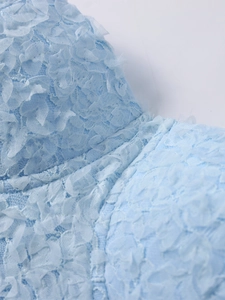 Detailed macro view of light blue lace fabric with 3D floral appliques and textures
