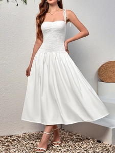 Detailed view of white smocked bodice and delicate tie straps on a lace dress