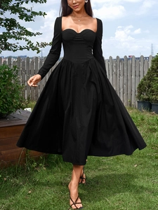 Détail de robe noire à manches longues avec décolleté en cœur et jupe évasée plissée