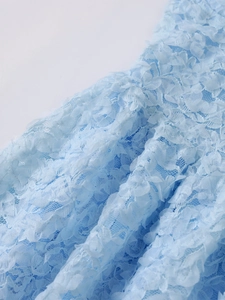 Macro shot of light blue floral lace fabric with rich textured layers on the dress
