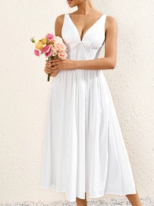 Détail de la robe blanche à col en V avec plis délicats et nœud décoratif miniature