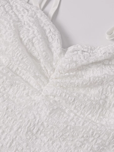 Detailed close-up of white crochet lace texture and V-neckline of a backless dress