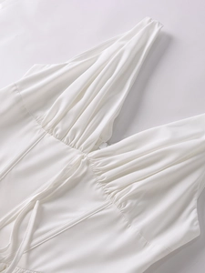 Détail du décolleté en V plongeant avec tissu plissé et laçage sur une robe blanche