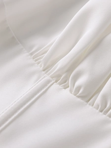 Détail rapproché des coutures plissées et de la texture sergée d'une robe trapèze blanche