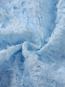 Detailed macro view of light blue lace fabric with 3D floral petals for party dresses