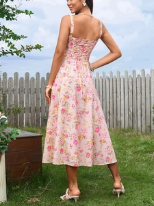 Detail of cross-straps on back of a pink floral midi dress in a sunny outdoor setting