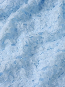 Detail of light blue 3D floral lace fabric with intricate mesh embroidery and soft texture