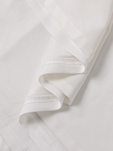 Detailed close-up of high-quality stitching and lace hem on white dress fabric