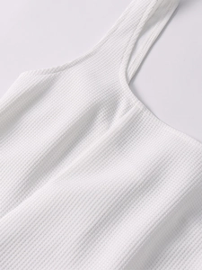 Detail of white waffle knit dress showing breathable texture and fine square neckline