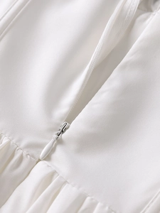 Gros plan sur la fermeture éclair invisible et les détails plissés de la robe blanche
