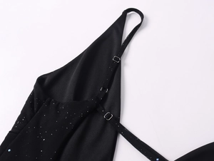 Détail d'une robe noire en tulle pailleté argent, col en V et boucle de sangle réglable
