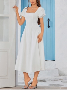 Detail of square neck and puff sleeves on a white A-line dress with Santorini background
