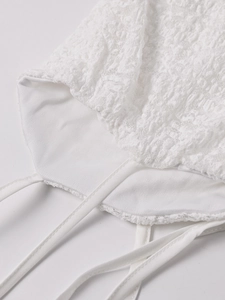 Close-up of intricate lace details and thin straps on a white evening maxi dress