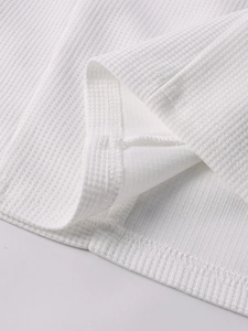 Detailed close-up of white waffle knit fabric texture and high-quality hem stitching