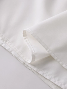Détail de l'ourlet à double couture et de la texture du tissu blanc de la robe longue