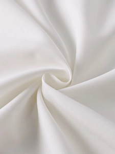 Macro du tissu blanc de la robe montrant une texture lisse et des plis élégants