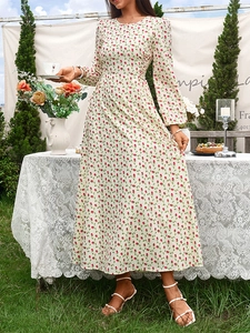 Détail de la robe maxi fleurie à manches longues avec taille ajustée dans un décor de jardin