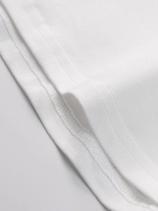 Detailed close-up showing precision double-needle stitching on a white knit hem