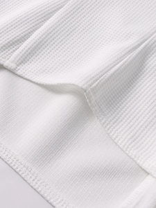Close-up of white waffle knit fabric texture showing honeycomb pattern and fine stitching