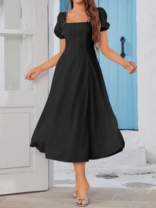Detail view of black A-line midi dress with square neck and puff sleeves against white wall