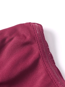 Detailed macro view of non-slip silicone strip on burgundy mesh corset dress fabric