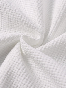 Detailed close-up showing the textured white waffle knit fabric of the dress