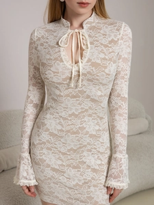 Close-up of white lace dress with V-neck tie, floral patterns and flared cuffs details