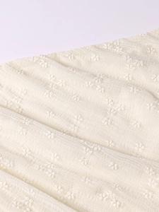 Detail of 3D lace fabric on a white bodycon dress with floral embroidery textures