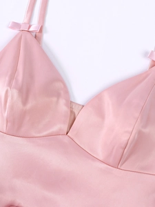 Detail of pink satin dress featuring delicate bow shoulder straps and V-neckline stitching