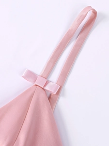Close-up of a pink satin dress showing delicate bow details and thin shoulder straps