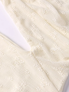 Close-up detail of cream 3D lace fabric and stitching on an elegant one-shoulder dress