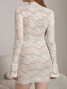 Detail of white lace dress showing floral mesh fabric and flared sleeves from back view