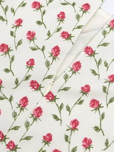Gros plan de la fermeture éclair invisible et de l'imprimé roses rouges sur tissu tissé