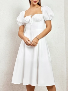 Détail de la robe blanche à manches bouffantes avec encolure carrée et cordon de serrage