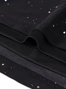 Détail du tissu en maille noire avec paillettes argentées et coutures de l'ourlet