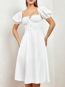 Détail d'une robe blanche milkmaid avec col carré, manches bouffantes et lien de buste