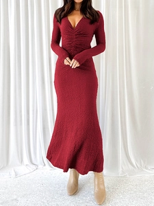 Détail du tissu en maille texturée bordeaux et du décolleté en V de cette robe ajustée