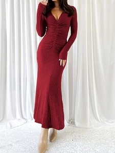 Détail de la texture froncée et du col en V sur une robe sirène en maille rouge foncé à manches