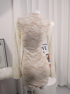 Detailed close-up of white crochet lace dress featuring elegant bell sleeves and floral patterns