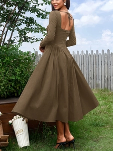 Détail d'une robe marron dos nu avec lacets et jupe plissée dans un jardin ensoleillé