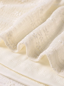 Detailed close-up of cream white lace fabric with intricate embroidery and soft lining