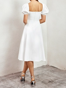 Détail d'une robe blanche élégante avec dos nu, fermeture éclair cachée et manches bouffantes