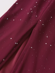 Close-up of burgundy mesh fabric with sparkling square sequins and fine seam details
