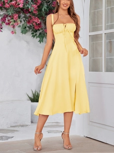 Detailed view of yellow sundress with gathered bust and slit hem in a vacation setting