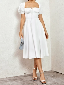 Détail de robe blanche avec encolure carrée, manches bouffantes et lien de serrage avant
