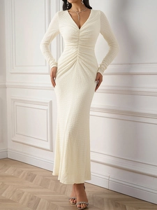 Détail de la robe en maille crème élégante avec des textures plissées et un décolleté en V