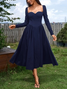 Détail d'une robe bleu marine à manches longues avec décolleté corset et plis sur pelouse