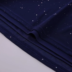 Close-up of deep blue mesh fabric with sparkling silver sequins and overlock stitching