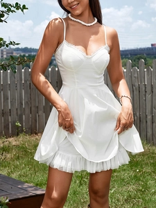 Detailed view of white slip dress with delicate lace trim and tiered mesh ruffle hem